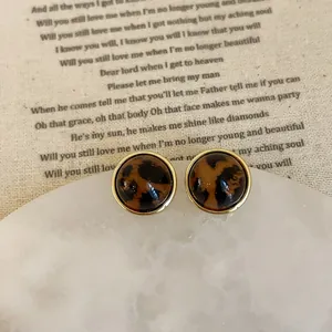 Macro view of leopard print resin earrings with elegant gold trim on retro fabric