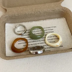 Detailed set of resin and silver rings on natural linen, featuring amber and olive tones