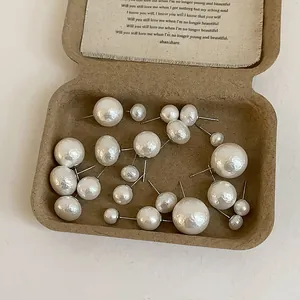 Detail view of various sizes of cream white pearl studs in a vintage aesthetic gift box
