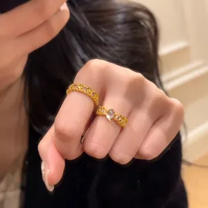 Detail of gold bow ring with gemstones and hollow textured band on hand