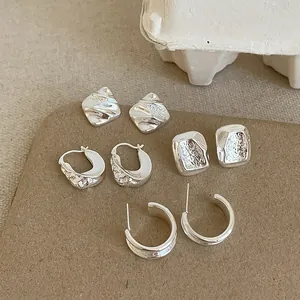 Minimalistisches Set silberner Ohrringe mit strukturierten Quadraten und glatten Creolen