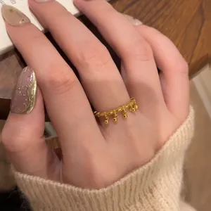 Detail of a vintage golden ring with a crown woven texture and small bead pendants
