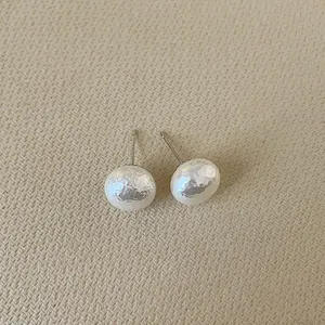 Detail of French vintage irregular pearl earrings with hammered texture on beige fabric