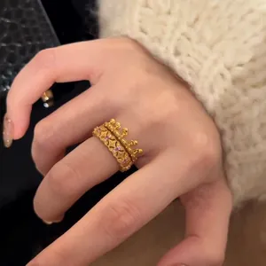 Detail of stacked gold crown ring and hollow engraved band with pink gemstones