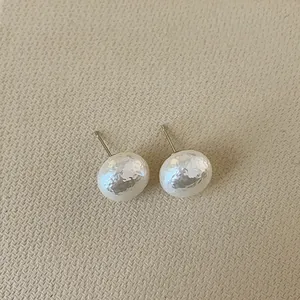 Close-up of French vintage irregular hammer texture pearl earrings with silver posts