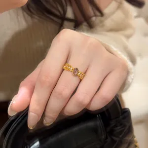 Detail of vintage gold ring with oval translucent stone and side zircon accents on finger