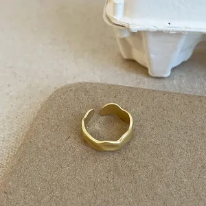 Nahaufnahme des matten goldenen Wellenrings mit strukturierter Oberfläche und offenem Design