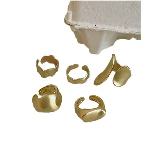 Set di cinque anelli dorati opachi irregolari e minimalisti da donna su sfondo bianco