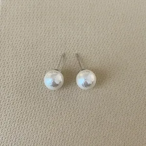 Close-up of polished 10mm white pearl stud earrings with 925 silver needles