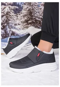 Dettaglio della calda fodera in peluche bianco nelle scarpe invernali grigie sulla neve