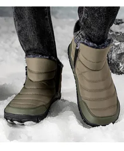 Detail of army green winter boot with thick fur lining and side zipper on snowy ground