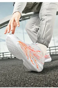 Macro shot of white running shoes with orange spray graphics and rotary buckle system
