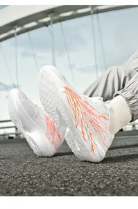 Close-up of white breathable running shoe with rotary dial lacing and orange patterns