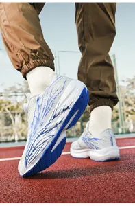 Low-angle close-up of white and blue running shoes on a red track showing sole grip detail