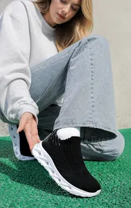 Vue de dessus de baskets en tricot noir avec semelles blanches sur piste de sport