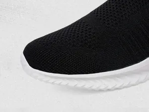 Detail van ademend zwart gebreid bovenwerk en witte antislipzool op casual schoenen