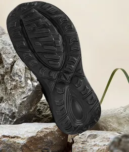 Detailed close-up of a black rubber shoe sole with non-slip traction patterns on rock