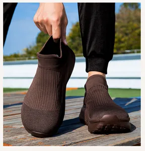 Detail eines dunkelbraunen Strick-Sneakers mit strukturierter Sohle auf Holzboden
