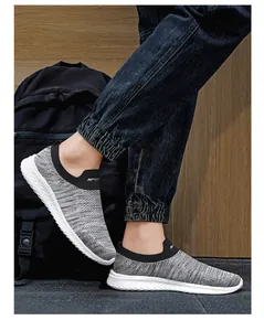 Detail van grijze fly-knit instapsneaker met SPORT-belettering en golvende witte zool