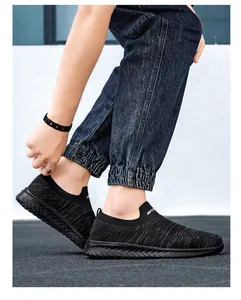 Detail van zwarte slip-on sneakers van ademend gebreid materiaal en SPORT-belettering