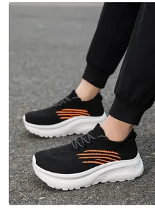 Detailansicht atmungsaktiver Mesh-Sneaker mit orangefarbenen Streifen auf Outdoor-Belag