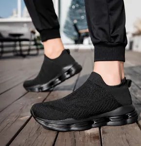 Detail view of black flyknit slip-on sneakers with breathable mesh on a wooden surface