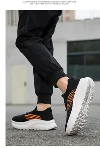 Dynamische Seitenansicht atmungsaktiver schwarzer Strick-Sneaker mit orangen Streifen