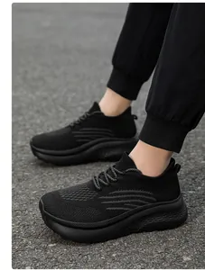 Nahaufnahme schwarzer, atmungsaktiver Fly-Knit-Sneaker mit dicker Dämpfungssohle auf Asphalt