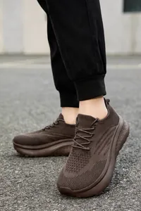 Nahaufnahme brauner atmungsaktiver Mesh-Sneaker mit dicker rutschfester Sohle auf Pflaster