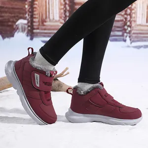 Gros plan de bottes d'hiver bordeaux avec doublure en fourrure et velcro dans la neige
