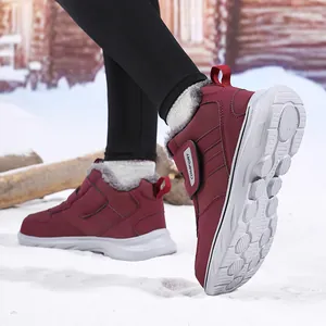 Gros plan de bottes de neige bordeaux avec doublure en fourrure grise et velcro sur neige