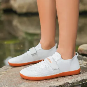 White breathable training shoes with orange non-slip rubber soles and Velcro straps