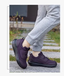 Detail of dark purple walking shoes with hook and loop straps on a model outdoors