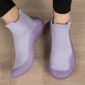 Scarpe da yoga in maglia viola con suole glitterate su pavimento in legno