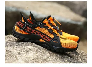 Detail of breathable orange mesh hiking shoe with quick-lace system on rugged rocks