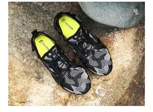 Detailed top view of breathable camouflage hiking shoes with quick-lace system on rocks