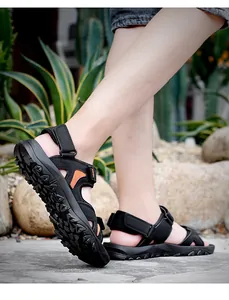 Detail of men's black sport sandals with orange mesh lining and rugged non-slip rubber soles