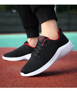 Zapatillas de running negras transpirables con borde rojo en acción sobre pista deportiva