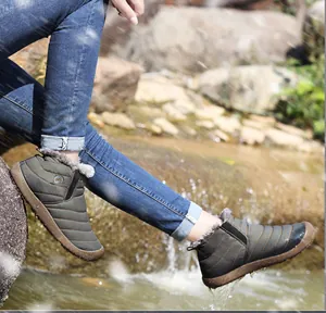 Close-up of olive green waterproof quilted snow boots with thick faux fur lining in the wild