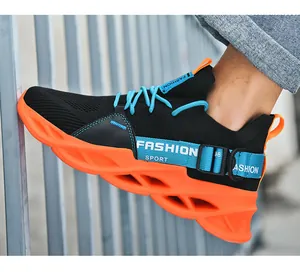 Detail of orange shock-absorbing sole and black fly-knit fabric on trendy sports shoes