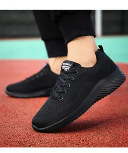 Detalle de zapatillas negras de malla transpirable sobre una pista de atletismo roja