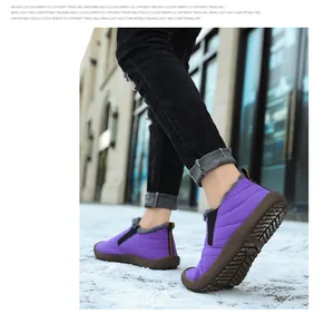 Close-up of purple winter boots with gray faux fur lining on snowy ground