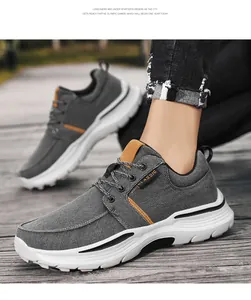 Vista detallada de zapatos de lona gris con detalles de cuero marrón sobre fondo de madera