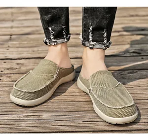 Detailansicht der Khaki-Canvas-Mules zum Slipper-Stil mit weißen Nähten auf Holzsteg