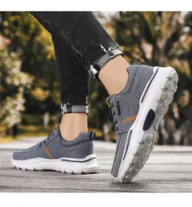 Detalle de zapatos de lona gris para hombre con ribete de cuero naranja en madera