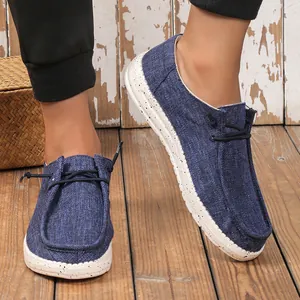 Close-up of blue canvas loafers with white speckled soles on a rustic wooden background