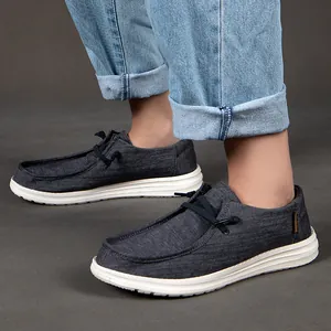 Mocassini da uomo in denim indossati con jeans chiari su fondo grigio con suola in gomma