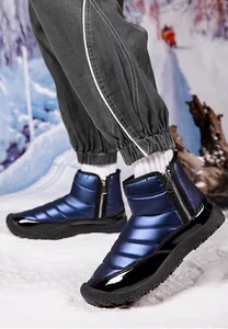 Close-up of waterproof snow boots with quilted blue fabric and non-slip rubber sole in snow