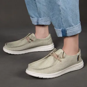 Dettaglio di mocassini in tela beige con suola in gomma bianca e jeans in denim