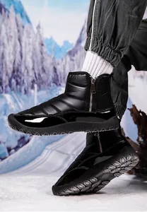 Close-up of black waterproof snow boots with quilted texture and side zipper on outdoor snow